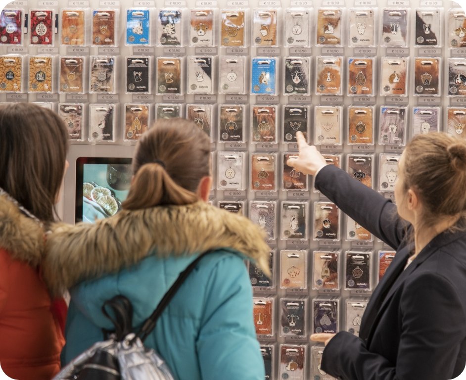 People choosing a pet ID tag from a wall filled with various designs.